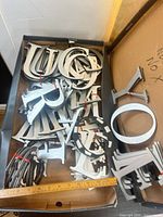 box containing numerous silver metal sign letters with wood backing