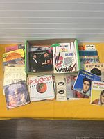 Overview of green box containing stack of approximately 40 7-inch records with several sleeves displayed