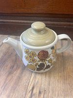 Front view showing floral pattern, spout, handle and lid