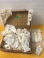 Open wicker basket with assorted lace and textile items visible