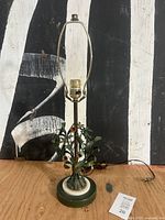 full view of lamp showing harp, stem, floral tole section and base