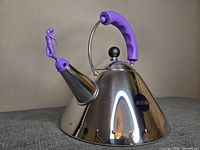 Full view of stainless steel kettle showing purple handle and whistle