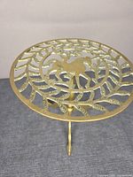 Full view of brass pedestal stand, showing round pierced top and tripod base