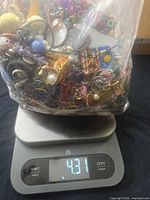 Bag of mixed jewelry on scale showing weight 4.31 lb