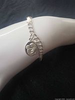 Bracelet on display form showing medal charm and chain