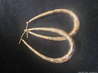 Both sterling silver teardrop hoop earrings on dark fabric background