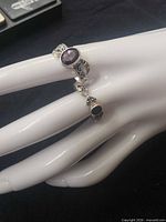 ring on display hand showing amethyst and onyx stones and ornate silver work
