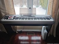Front view of Casio PX-555R keyboard on stand with music stand and CD-ROM visible