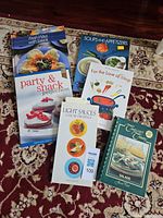 All six cookbooks arranged on rug cover sides up