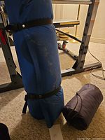 Rolled blue sleeping bag with compression straps next to purple stuff sack