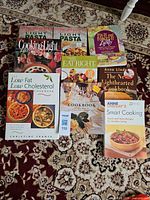 Group shot of all nine cookbooks laid out on patterned rug showing fronts and titles