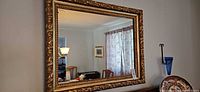 Front view of large horizontal gold gilded ornate framed mirror hung on wall