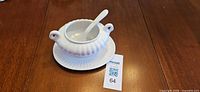 Gravy boat on saucer with spoon inserted, full view