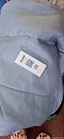 Rolled light blue queen comforter showing overall color and material