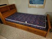 Full view of twin bed frame showing bookcase headboard, footboard, three drawers, mattress in place