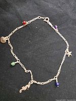Full view of sterling silver anklet laid flat showing all charms and clasp