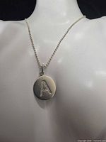 Close-up of pendant on mannequin showing bead chain and letter A with stones