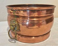 Front view showing copper body and one brass lion head ring handle