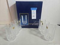Six tumblers with gold stickers arranged around original blue Cristal d'Arques box