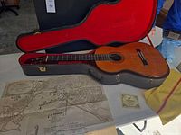 Guitar in open hard case with paperwork and map on table