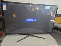 Front view of powered-on 50" Samsung plasma TV on stand
