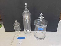 Three glass apothecary jars with lids, front view