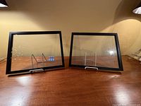 Two black double-sided clear frames on table