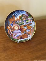 Front of Franklin Mint collector plate showing teddy bear picnic scene on display stand