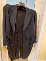 Front view of black tailcoat on hanger showing peak lapels and double-breasted front