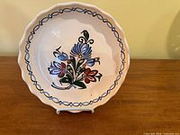 Full view of plate on stand showing design and scalloped rim