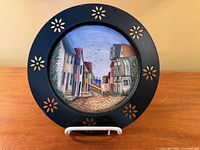 Front view showing painted village scene and pierced floral rim