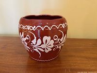 Front view of redware vase showing floral white slip decoration