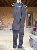 Full view of black sleeveless neoprene wetsuit hanging