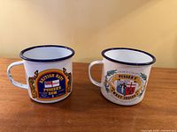 Front view of both enamel mugs showing crests