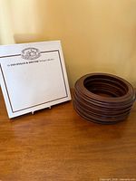 Stack of unboxed wooden plate holders beside branded box