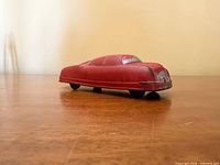 Side view of red rubber toy car showing profile and wear