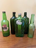 Five green glass bottles including Catawba wine and partial gin label