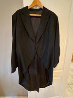 Front view of black wool tailcoat on hanger