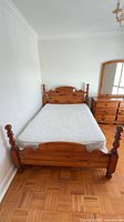 Full view of assembled pine four-poster bed with mattress