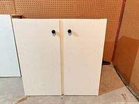 Front view of white two-door cabinet with black knobs