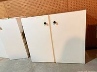 Front view of white cabinet with two doors and black knobs