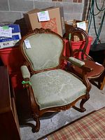 Front angle of carved wood arm chair with green upholstery