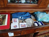 Drawer view showing placemats, coasters, place-card holder boxes, glass dishes, silver-plate trivets, butter dishes