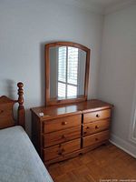 Dresser with mirror against wall next to bed