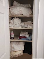 Closet view showing duvet, stacked white linens, towels and blanket