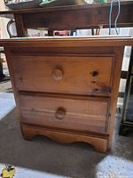 Front view showing two drawers, knobs, scalloped base