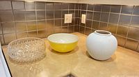 Group shot of crystal bowl, Pyrex bowl, and pottery vase on countertop