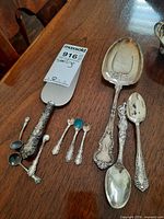 Group showing cake server, miniature spoons, serving spoon and teaspoons