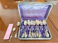 Case open displaying 11 spoons inside on purple lining