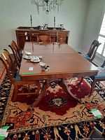 Top view of wood dining table with one leaf inserted, double pedestal legs visible